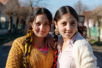 Kaksi romanityttöä hymyilevät kuvaajalle.